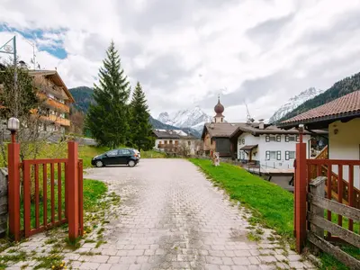 a street in a village with a fence and a car at Apartment Appartamento Crepaz by Interhome in Canazei