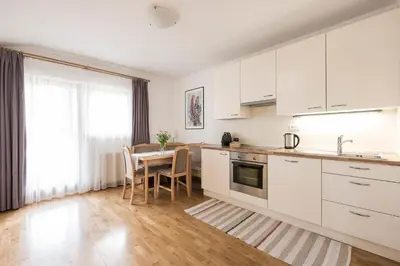 a kitchen with white cabinets and a table with chairs at Ferienwohnungen Alber in Rablà