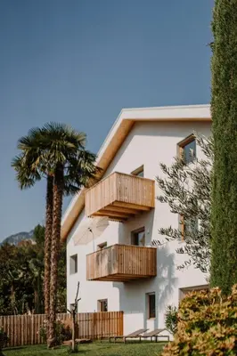 a white building with wooden balconies and a palm tree at die Waltraud im Refugium Rochus in Pianizza di Sopra