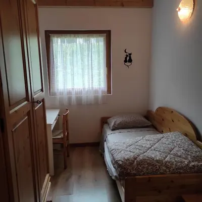 a bedroom with two beds and a desk and a window at Casa San Valentino Dolomiti Val di Zoldo in Val di Zoldo