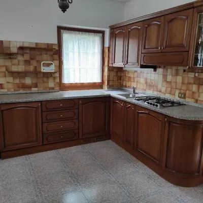 an empty kitchen with wooden cabinets and a window at Casa San Valentino Dolomiti Val di Zoldo in Val di Zoldo