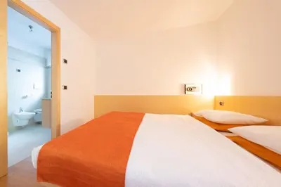 a bedroom with two beds and a bathroom at Cesa Delba in Canazei