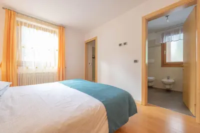 a bedroom with a bed and a bathroom with a toilet at Cesa Delba in Canazei