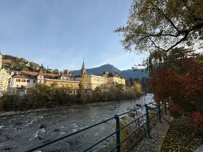 a river in front of a city with buildings at Darling Home in Merano