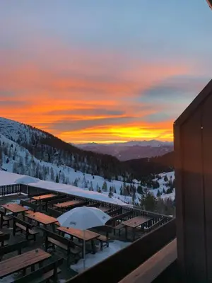 a group of tables and umbrellas in the snow at sunset at Darling Home in Merano