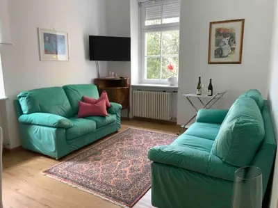 a living room with a green couch and a rug at Darling Home in Merano
