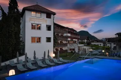 a hotel with a swimming pool in front of a building at Hotel Sunnwies in Schenna