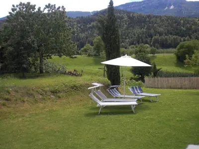 a group of chairs with an umbrella in the grass at Residence Rebgut in Tesimo