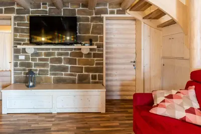a living room with a red couch and a stone wall at Chalet alla Perla, Grumes in Grumes