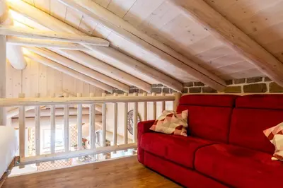 a red couch in a room with wooden ceilings at Chalet alla Perla, Grumes in Grumes