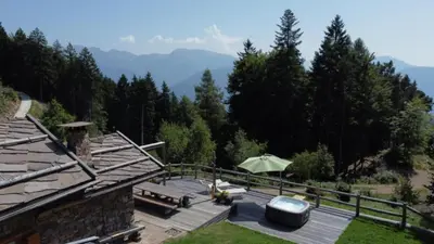 a wooden deck with an umbrella and a view of mountains at Chalet alla Perla, Grumes in Grumes