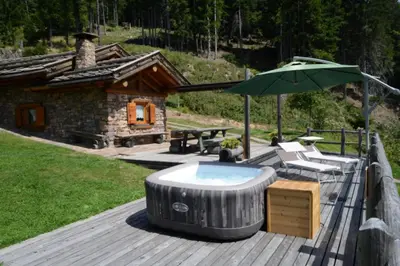 a hot tub and an umbrella on a wooden deck at Chalet alla Perla, Grumes in Grumes