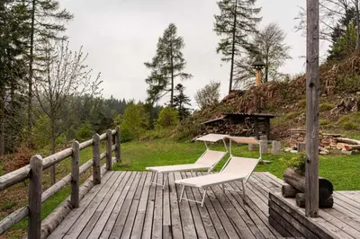 a wooden deck with two chairs and a table at Chalet alla Perla, Grumes in Grumes