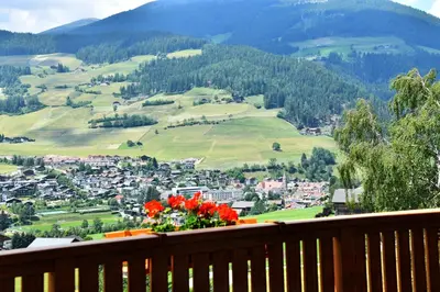 a view of a town from a balcony with red flowers at Botenhof - Urlaub auf dem Bauernhof - Agriturismo in Sarntal
