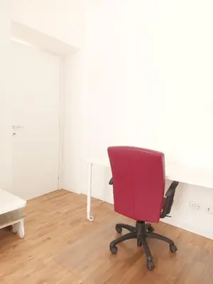 a red chair sitting in a room with a desk at Apartment Ca' de Bezzi in Bolzano