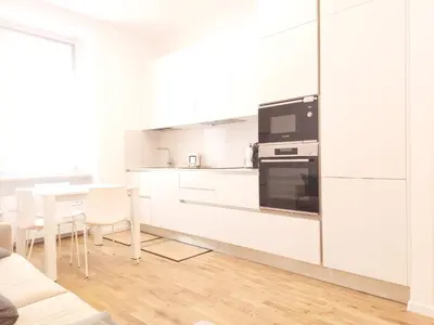 a kitchen with white cabinets and a table with chairs at Apartment Ca' de Bezzi in Bolzano