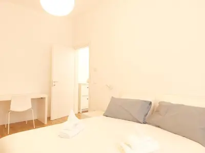 a white bedroom with a white bed and a desk at Apartment Ca' de Bezzi in Bolzano