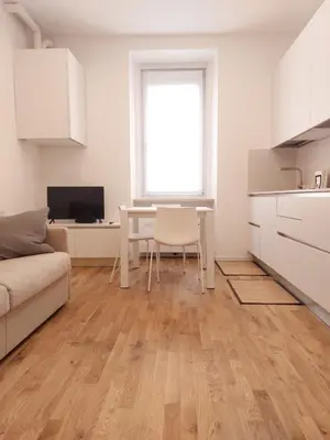 a white living room with a table and a kitchen at Apartment Ca' de Bezzi in Bolzano