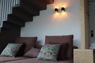 a couch with pillows and lights on a wall at Hillepranter in Marlengo
