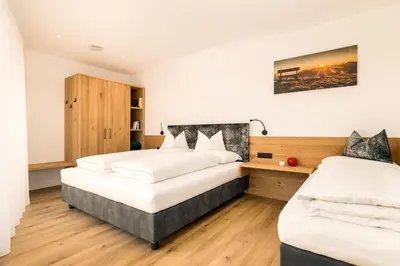 two beds in a room with white walls and wooden floors at Apartments Baumann Living in Rodengo