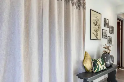a living room with a curtain and a table with at Mali Apartments Garden Suite in Tirolo