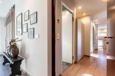 a hallway with white walls and a door with a vase on a table at Mali Apartments Garden Suite in Tirolo