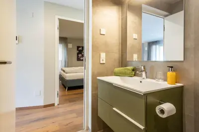 a bathroom with a sink and a mirror and a bedroom at Mali Apartments Balcony in Tirolo