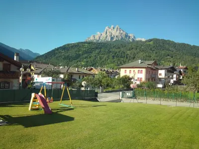 a park with a playground with a mountain in the background at Appartamenti Primiero in Fiera di Primiero