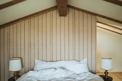 a bed with two lamps in front of a striped wall at Schnitzbichlhof in Lana
