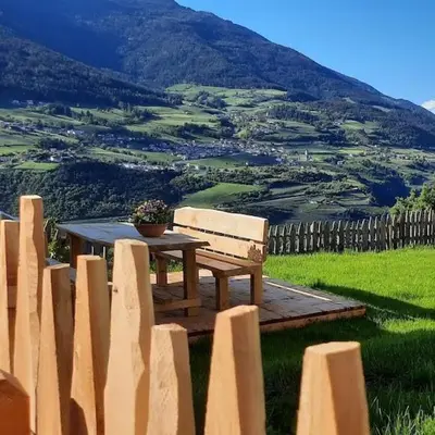 a wooden table and bench in front of a fence at Moarhof Gufidaun in Chiusa