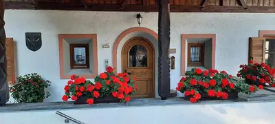 a building with red flowers in front of a door at Moarhof Gufidaun in Chiusa