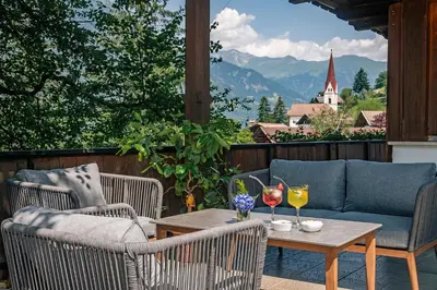 a patio with chairs and a table with wine glasses at Ursulas Idyll in Saltusio