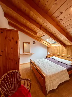 a bedroom with a large bed and a wooden ceiling at Pragma Apartments - Appartamento Genziana in Predazzo