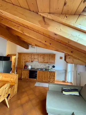a living room with a couch and a kitchen at Pragma Apartments - Appartamento Genziana in Predazzo