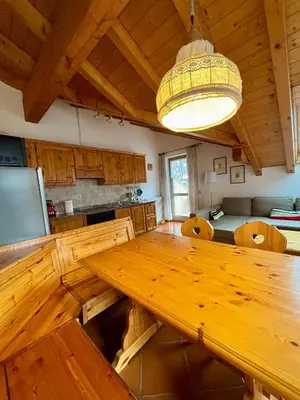 a large wooden table in a kitchen with a ceiling at Pragma Apartments - Appartamento Genziana in Predazzo