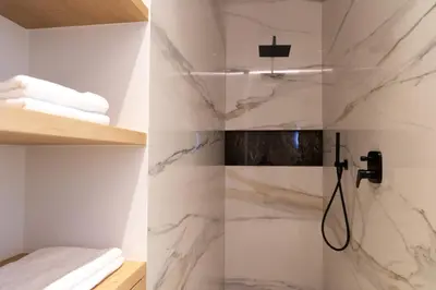 a bathroom with white marble walls and a shower at Luxury Apartment Villa Ortler in Merano