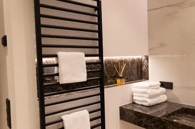 a bathroom with a black and white towel rack at Luxury Apartment Villa Ortler in Merano