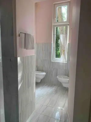 a pink bathroom with two toilets and a window at Helles Apartment in historischer Villa in Merano