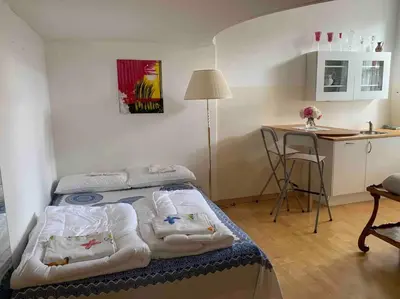 a bedroom with a bed and a kitchen with a table at Helles Apartment in historischer Villa in Merano