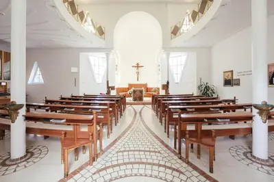 a church with wooden benches and a cross in the middle at Gästehaus Salvatorianerinnen in Merano