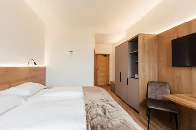 a bedroom with a bed and a desk and a tv at Gästehaus Salvatorianerinnen in Merano