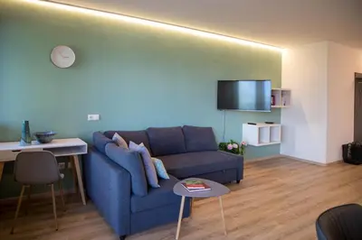 a living room with a blue couch and a table at Appartement 7 in Caldaro