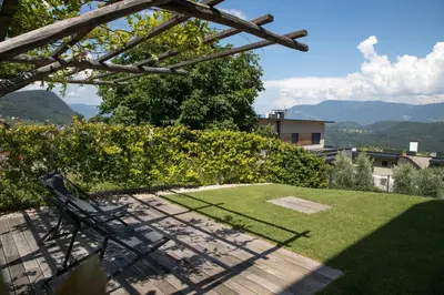 a garden with a bench and grass and mountains at Appartement 7 in Caldaro