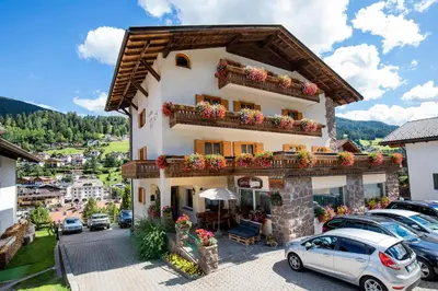 a building with cars parked in a parking lot at Garni Rives in Ortisei