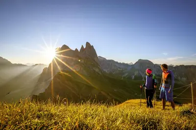 two people standing on a mountain looking at the sunset at Garni Rives in Ortisei