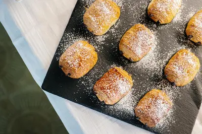 a tray filled with sugar covered pastries on a table at Garni Rives in Ortisei