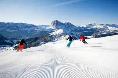 three people are skiing down a snow covered mountain at Garni Rives in Ortisei