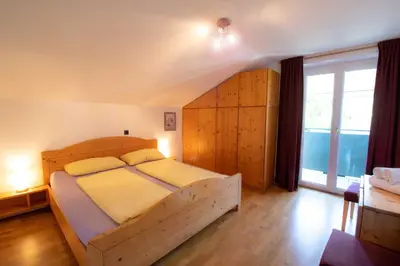 a bedroom with a wooden bed and a large window at Melaniesguesthouse 4 Zimmerwohnung in Caldaro