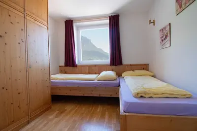 two beds in a room with a window at Melaniesguesthouse 4 Zimmerwohnung in Caldaro