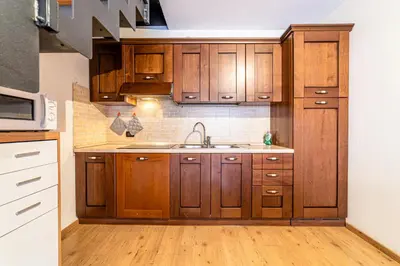 a kitchen with wooden cabinets and a sink at Appartamento Dolomiti Alleghe in Alleghe